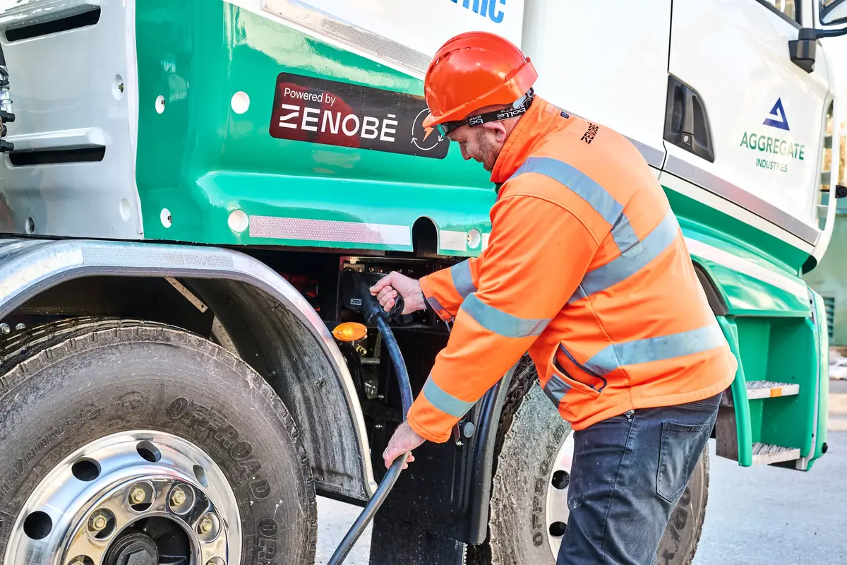 Zenobe employee plugs in charger for electric concrete mixer
