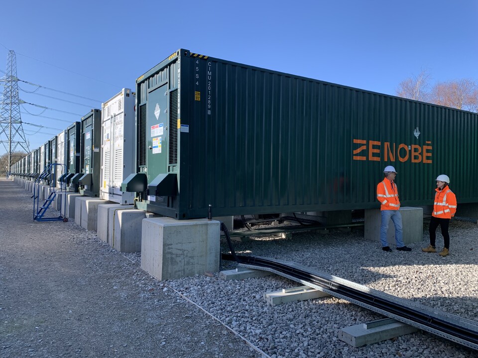 Two people standing in front of a Battery Storage unit