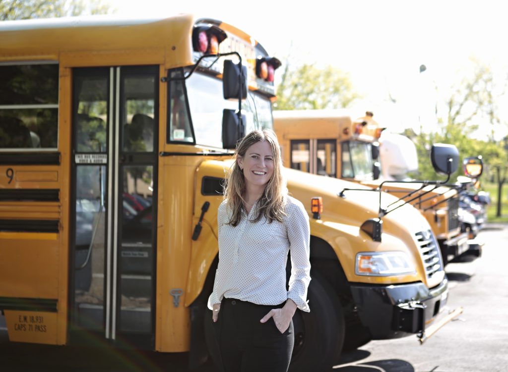 Zenobē representative standing in front of yellow electric school buses.