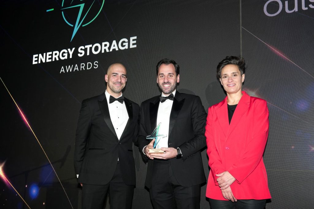 Semih Oztreves, Global Director of Network Infrastructure at Zenobē, holding the Energy Storage Award 2024, alongside two colleagues at the awards ceremony.