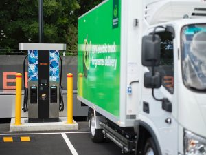 Close-up of an electric delivery truck connected to a Zenobē charger at a Woolworths shared charging hub in Australia, showing charging unit and cab detail.